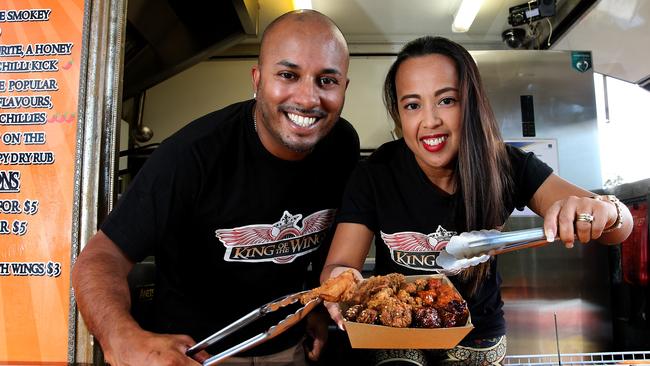 Dylan and Katrina Pires behind the King Of The Wings food truck serving window holding tongs and a tray of wings