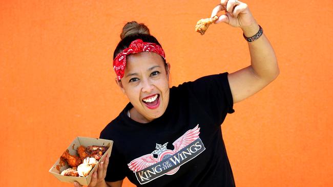 Katrina Pires in a King Of The Wings T-shirt holding a chicken wing high after the Wingfest podium
